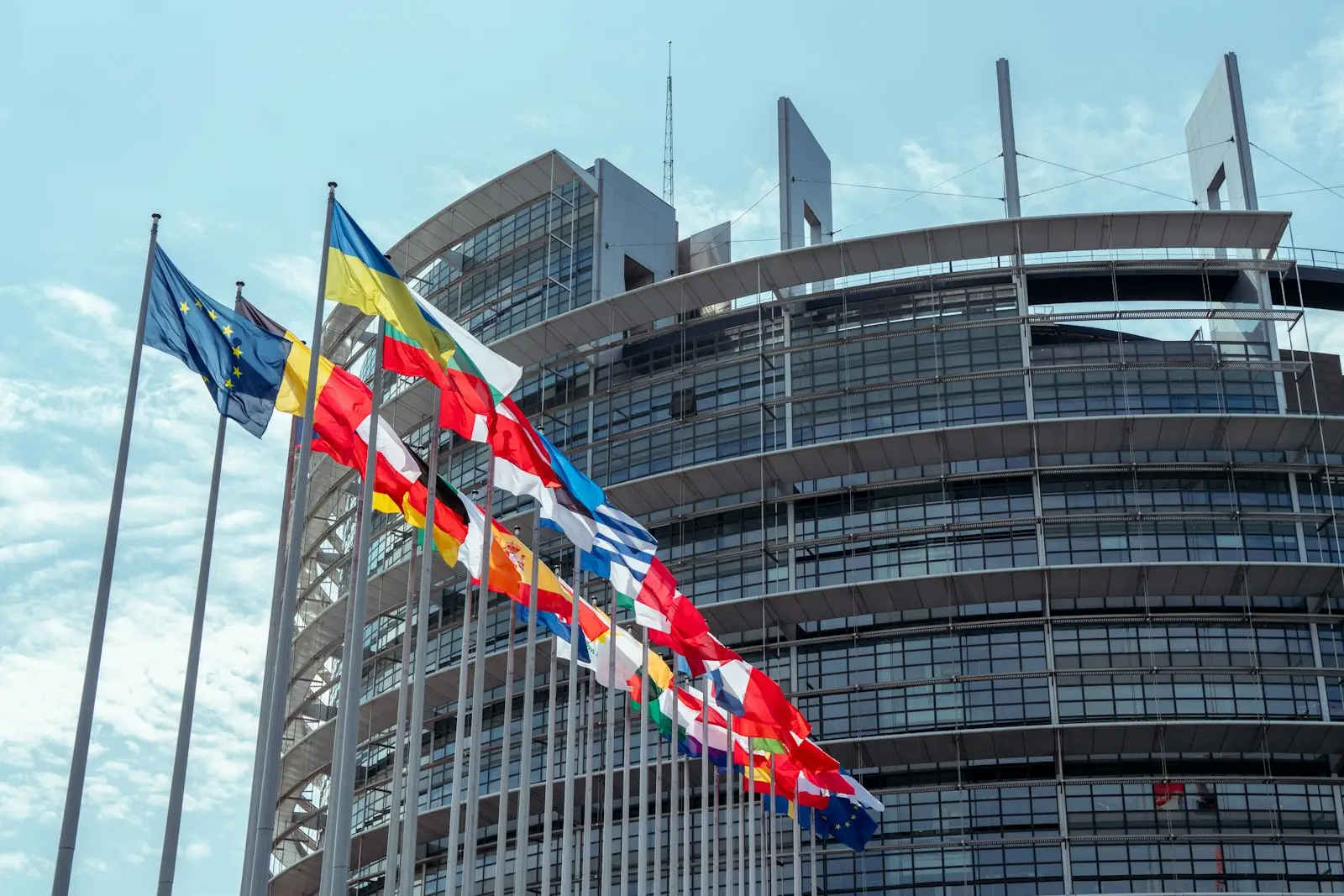 Απαγόρευση θερμικών 2035: Αναβολή ψηφοφορίας στην ΕΕ Κτίριο με πολλές σημαίες της ΕΕ, σχετικά με την απαγόρευση θερμικών 2035